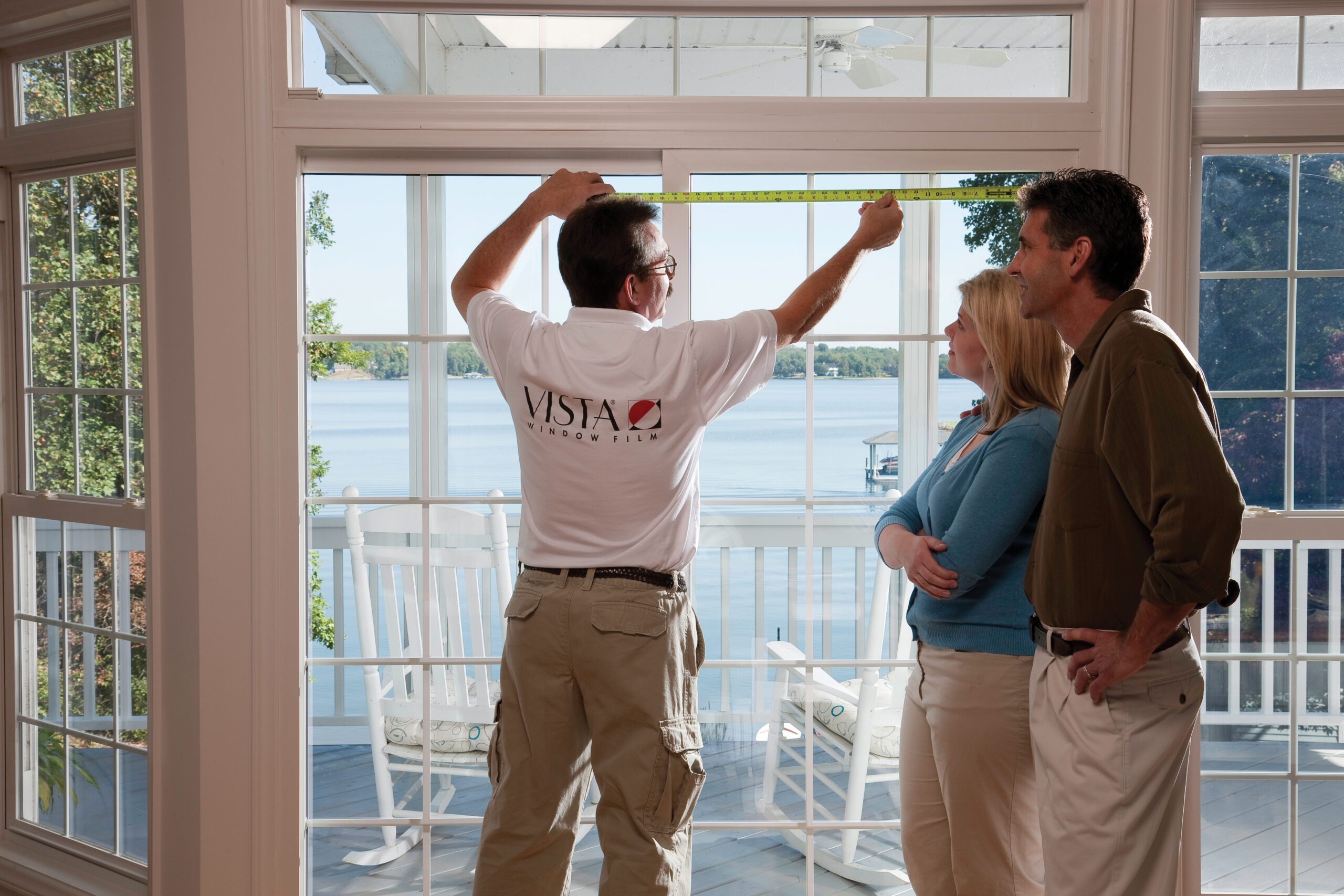 A worker measuring windows for treatment.